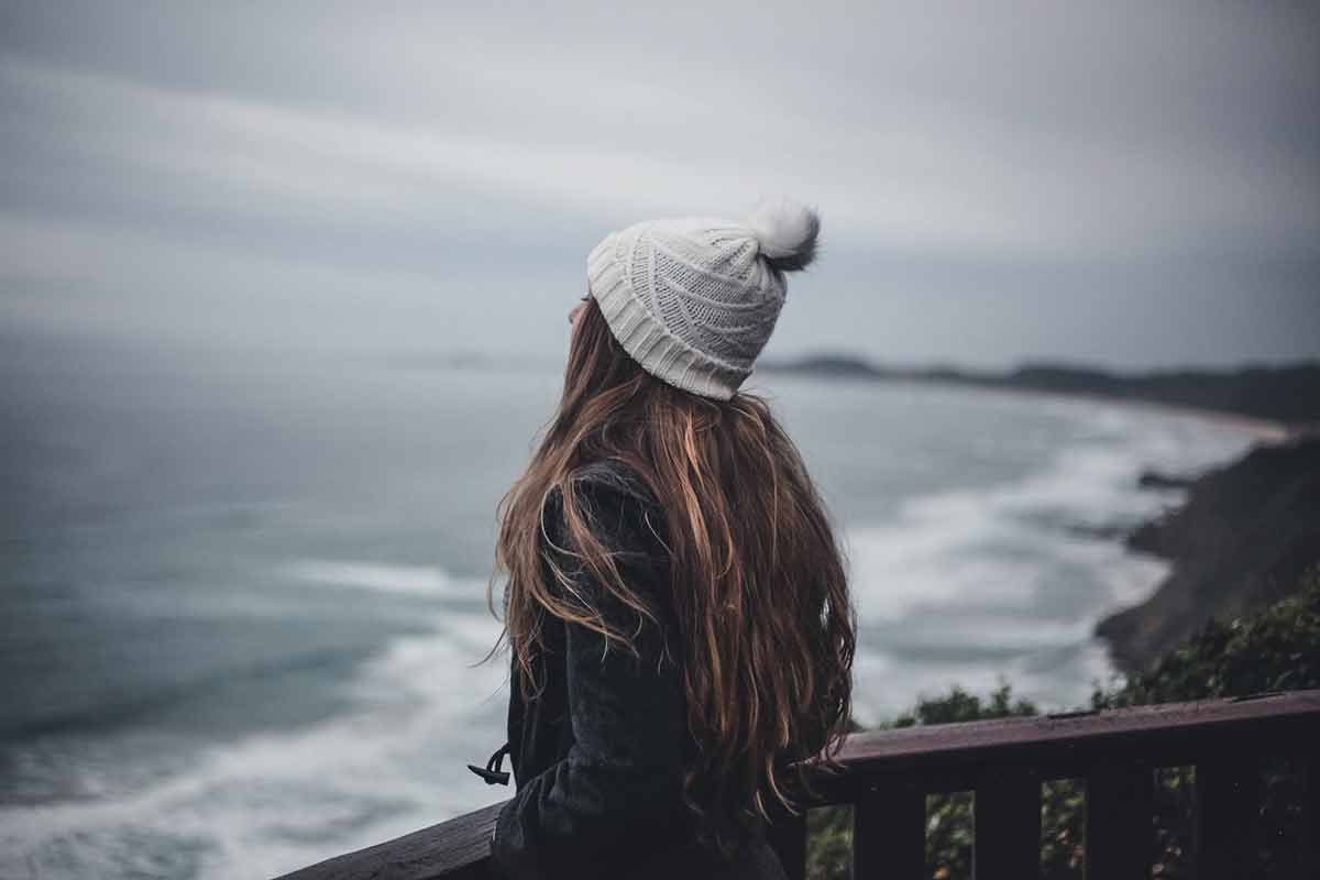 girl overlooking ocean with winter hat